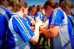 women's gaelic players huddle with hands in