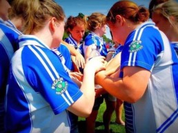 women's gaelic players huddle with hands in